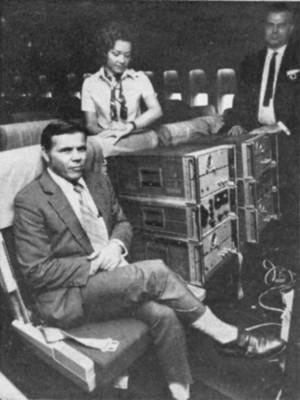 Figure 6: Les physiciens Joseph Hafele (né en 1933) et Richard Keating à bord d’un avion de ligne, avec leurs horloges atomiques au césium (photo de la revue Popular Mechanics, janvier 1972)
